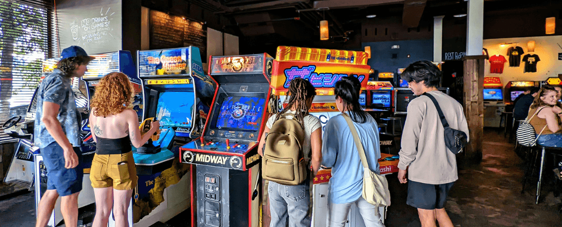Young people playing classic arcade games in arcade setting